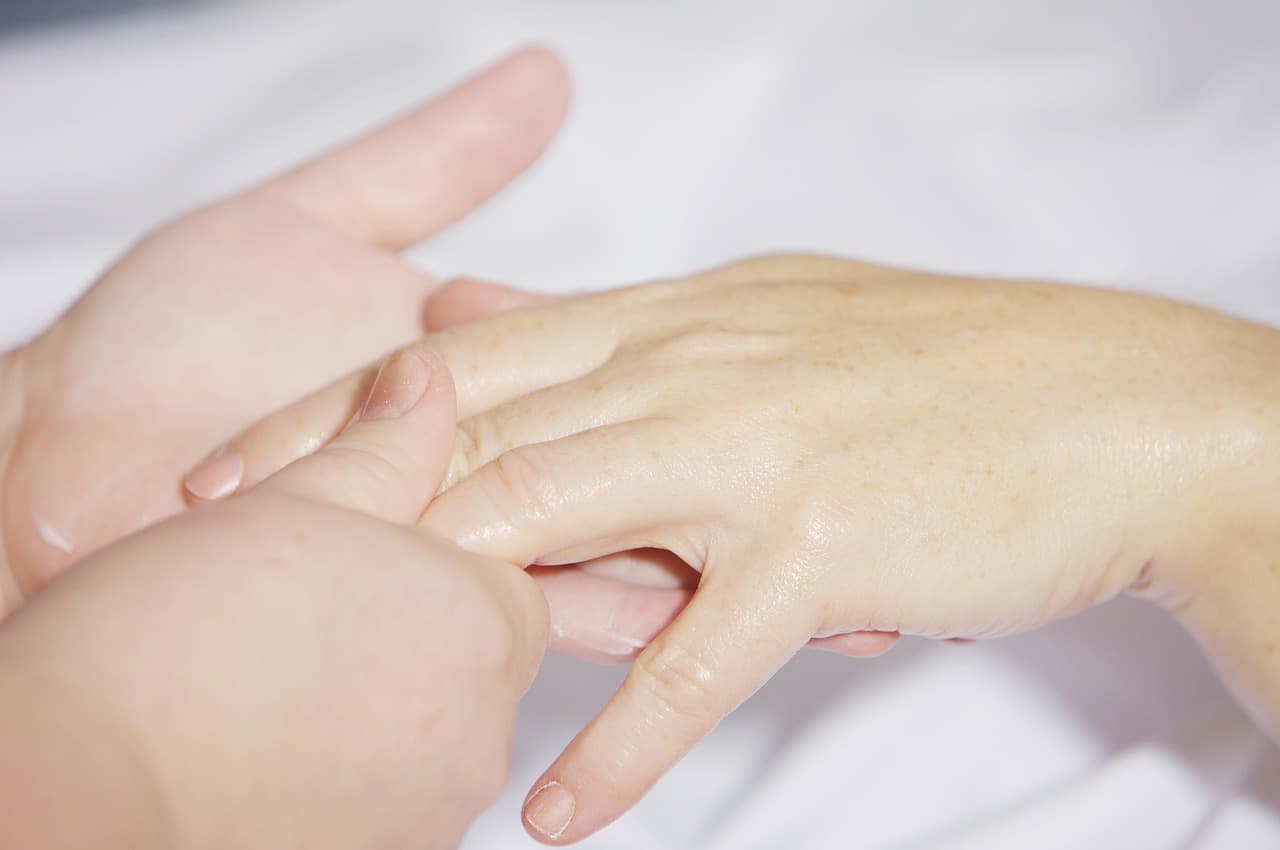 One pair of hands gently massaging another during a manicure