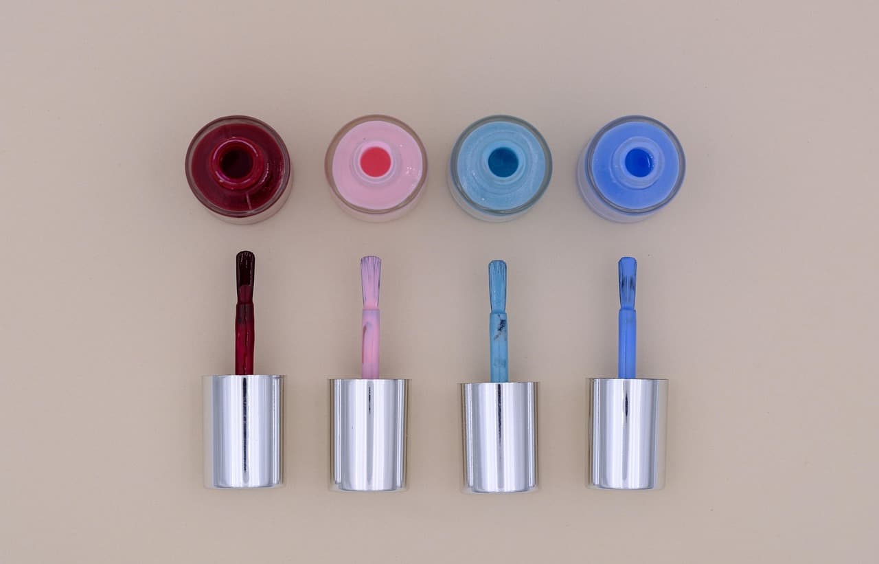 Four open nail polish bottles from above: berry, pale pink, sky blue and cobalt